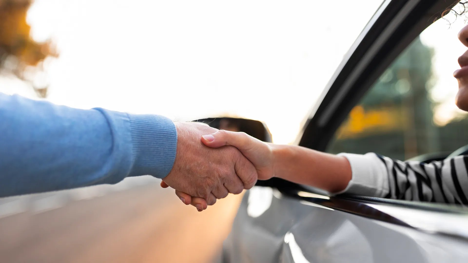 Aperto de mãos selando negócio de seguro automotivo - Confiança e parceria