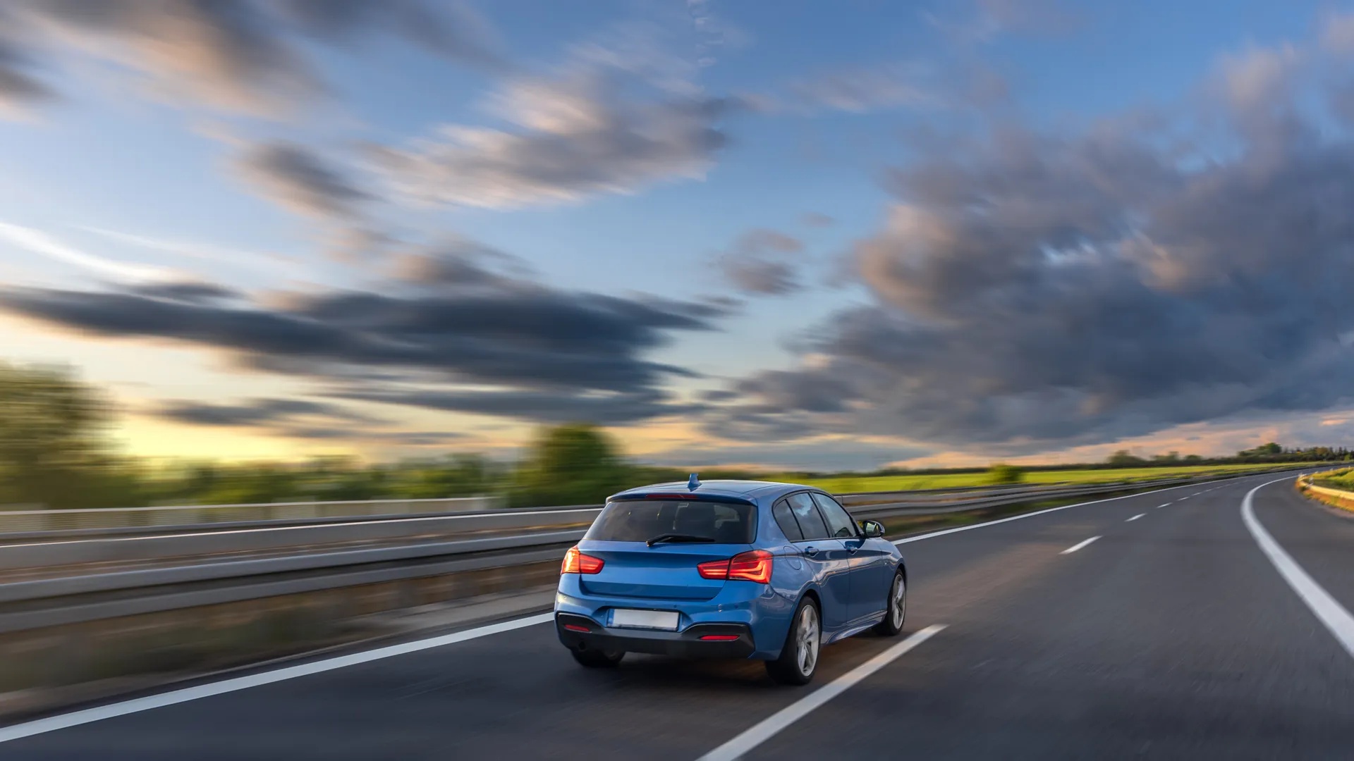 Carro azul em movimento na estrada ao entardecer - Seguro automotivo